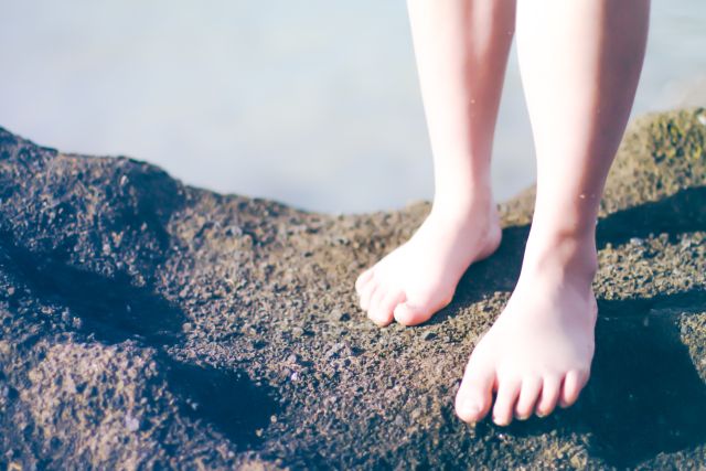 woman's bare feet on rocks